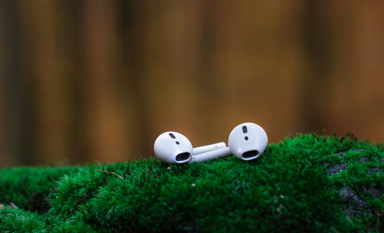 why-choose-us Close-up of wireless earbuds resting on vibrant green moss, showcasing portable audio technology.